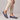 Blue woven loafers worn with beige pants on a neutral background